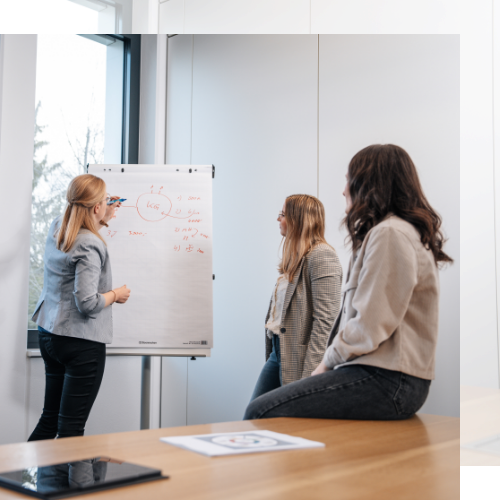 drei junge Damen arbeiten gemeinsam an einem Whiteboard