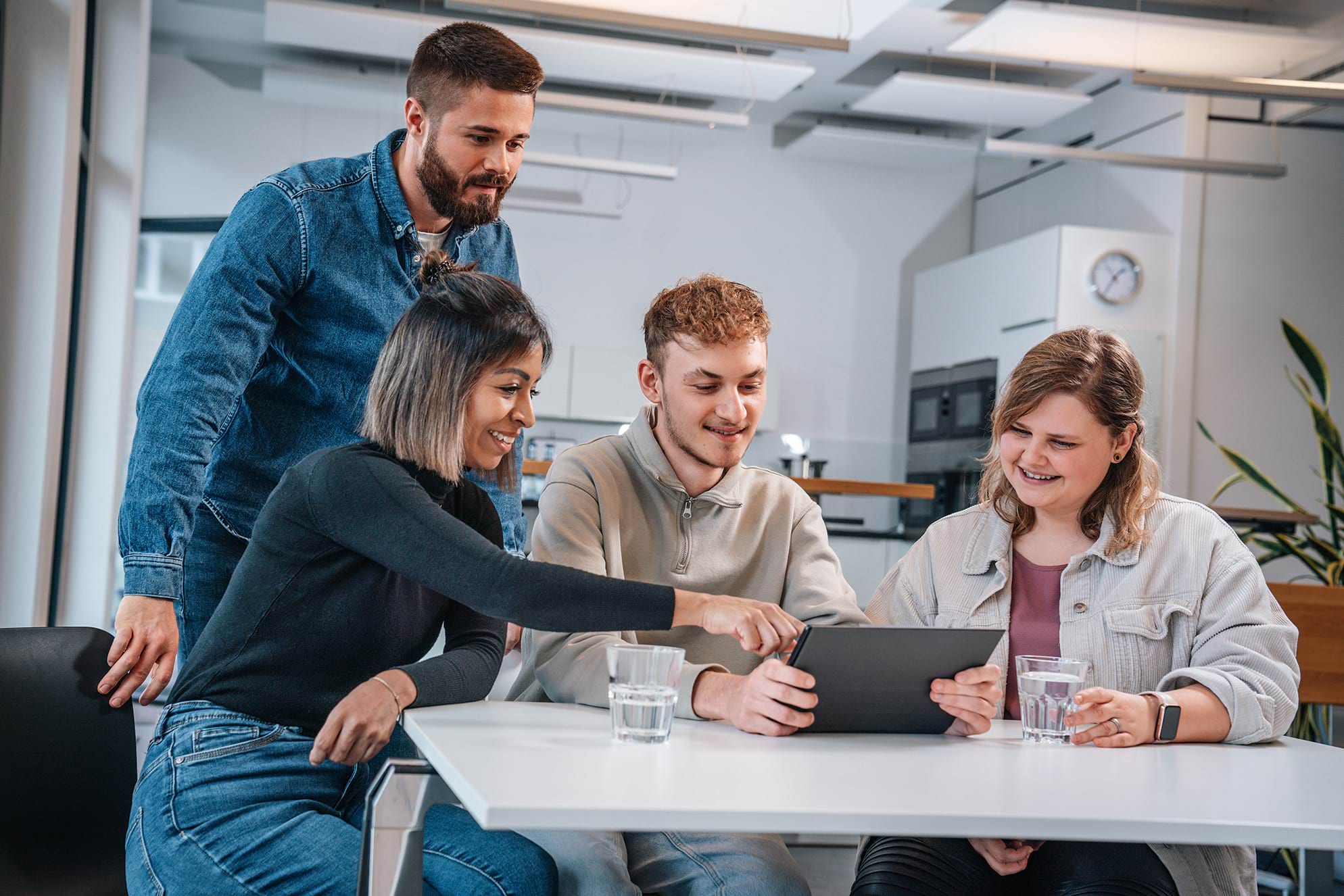 ein junges Team arbeitet gemeinsam am Tisch und besprechen sich