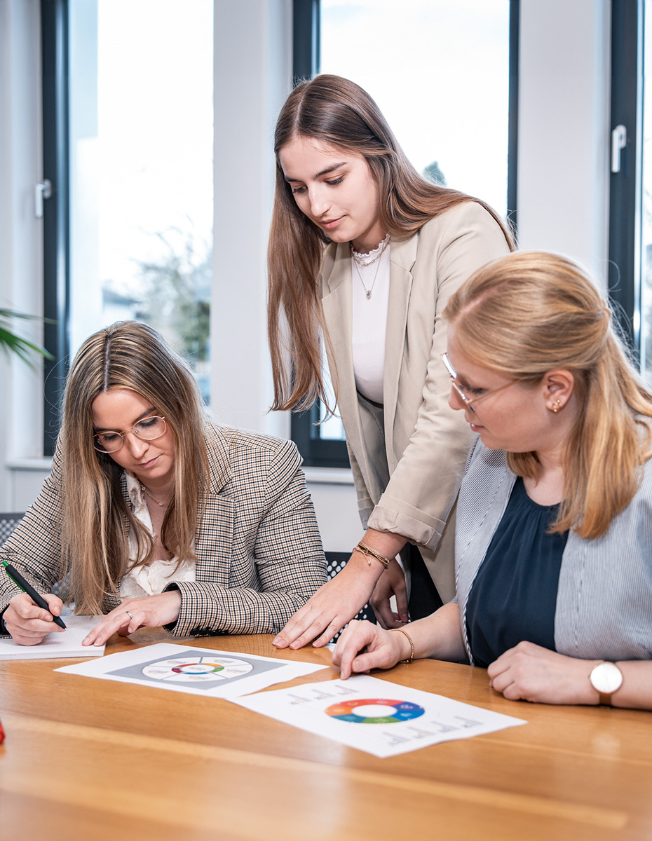 drei junge Damen werten Daten aus und arbeiten gemeinsam