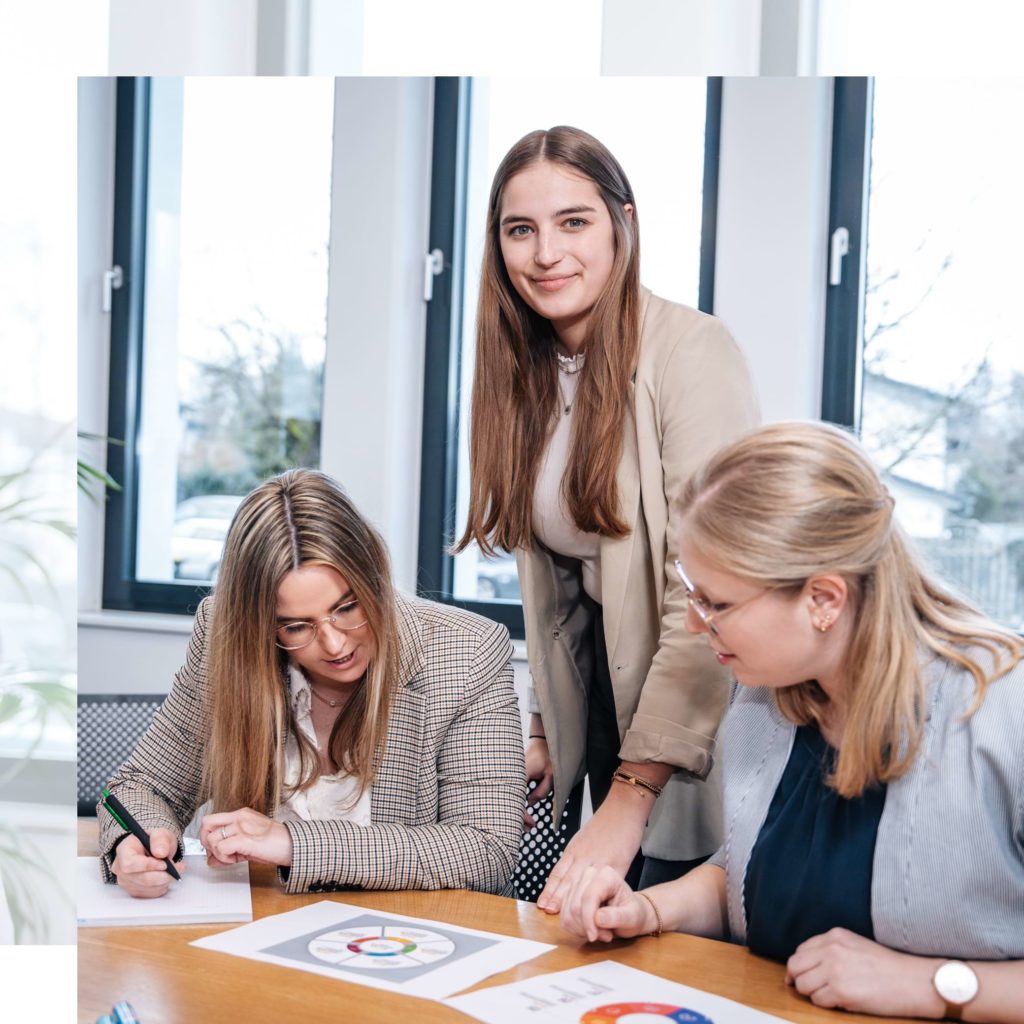 drei junge Damen werten Daten aus und arbeiten gemeinsam